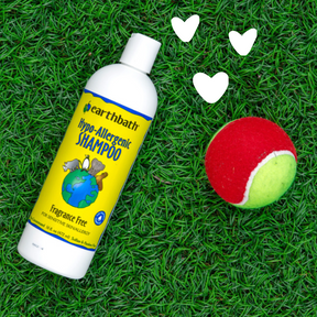 Earthbath hypo-allergenic shampoo bottle on grass with a tennis ball