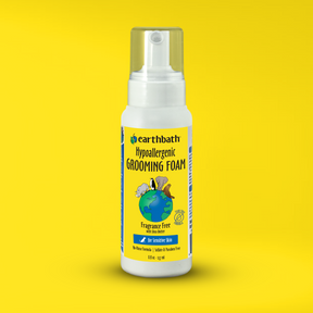 A bottle of earthbath Hypoallergenic Grooming Foam for dogs. The bottle is transparent with a white label, and the foam inside is visible on a yellow background